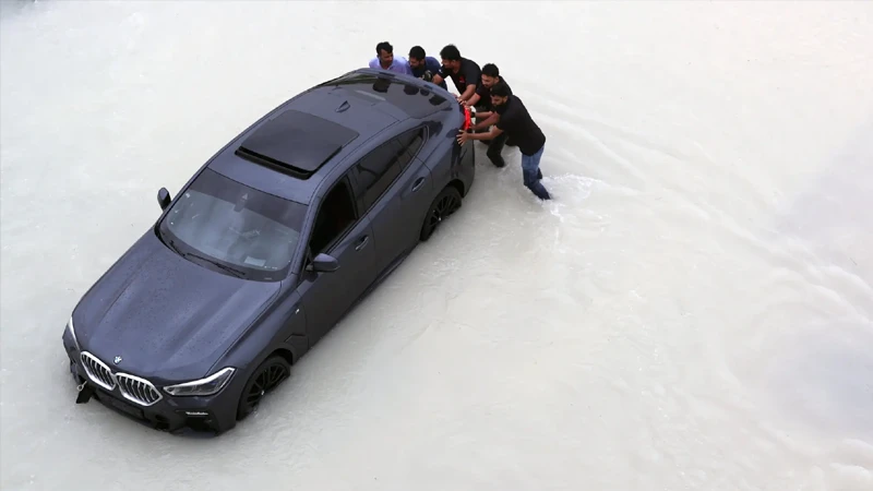 বৃষ্টির পানিতে আটকে যাওয়া এক গাড়ি ঠেলছেন কয়েকজন